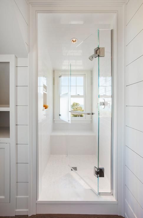 A seamless glass door opens to a walk-in shower fitted with white .